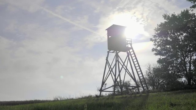 Wood observation watch tower against background with sunbeams and cloudy sky