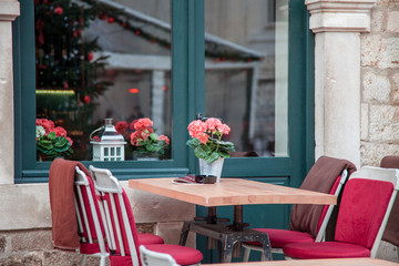 Street cafe at Christmas market in old town. Table and chairs with plaids near wooden window. Cozy festive atmosphere in Dubrovnik, Croatia.