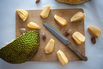 Ripe Jackfruit pieces with jackfruit pods on wooden desk with knife isolated on white