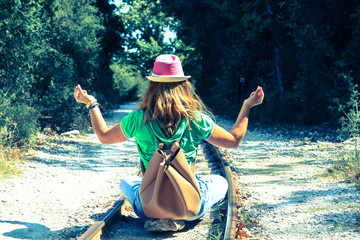 One woman sitting on the rail tracks and turned against camera