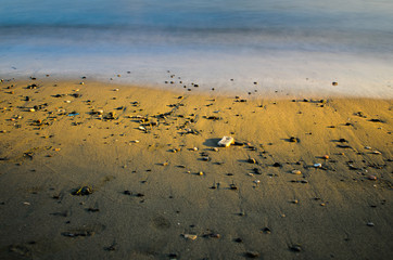 A shot of the sea, the golden sand and the sun hitting only the middle of the   scene