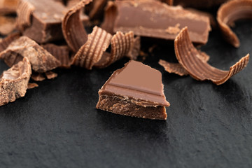 Broken chocolate pieces and chocolate shavings on a dark background