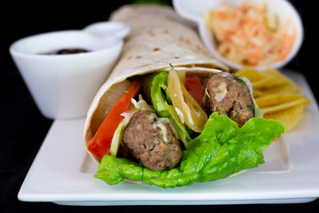 Delicious meatball wrap with salad inside with isolated black background