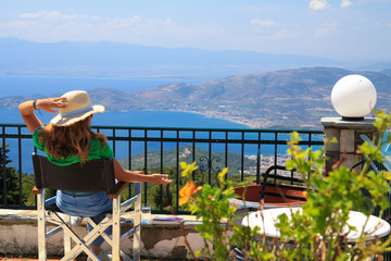 One female sitting on a terrace balcony in a summer resort overlooking the sea