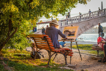 Woman artist draws Venetian canal and beautiful bridge