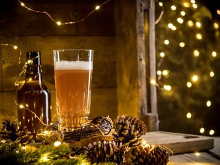 Papier Peint photo Bière Bière en verre sur fond de bois avec des lumières de Noël et des pommes de pin