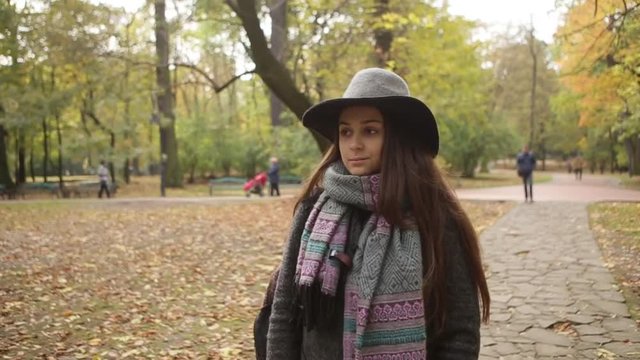 Serious young girl with hat in coat walk in autumn park attractive beautiful caucasian fall female forest hair yellow cheerful clothing cute happy leaf orange outdoor people close up