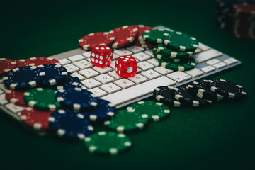 Fototapeta premium Side view of a green poker table with some poker cards on a keyboard. Betting on-line concept