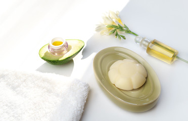 Obraz na płótnie Canvas Beauty concept avocado, skin care facial essence oil, soap, lily flower and towel on white background. Facial treatment preparation for cosmetic clinic. beauty spa. copy space. Selective focus, trend