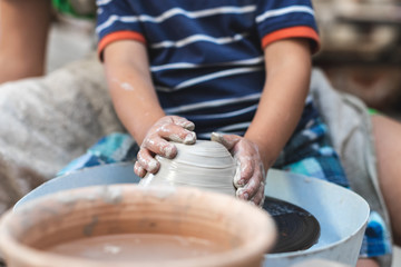 Master class concept. Small kid sit inside workspace create and modeling bowl or other product by hands