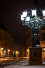 Fototapeta premium Historic and ornamental gas candelabrum in snowy street of Prague.