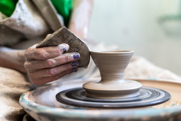 Master class concept. Concentrated focused calm accurate lady in her workwear she sit inside workspace behind circular wheel correct form tableware used special tool