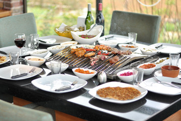 Traditional Cypriot meze and mix meat and chicken kebab table with charcoal barbecue on the table for self cooking during the eating time