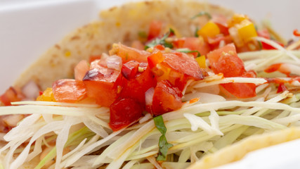 A soft taco shell with cabbage slaw and colourful red and orange pico de gallo using tomatoes and bell peppers. Taco came from a food truck.