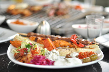 Traditional Cypriot meze and mix meat and chicken kebab table with charcoal barbecue on the table for self cooking during the eating time