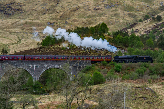 Glenfinnan Viaduct, Scotland. Travel/tourist destination in Europe. Old historical steam train riding on film scene famous viaduct bridge. Highlands, mountains, outdoor background. © Dajahof