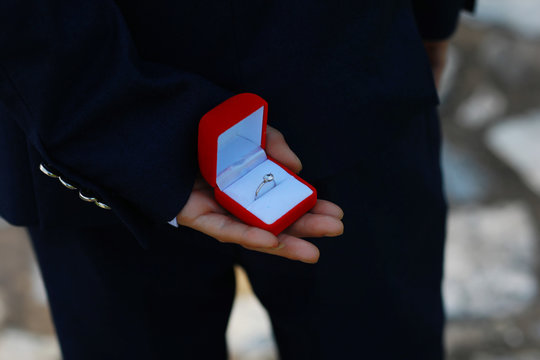 romantic man making a marriage proposal. picture of man with gift box in suit. picture of couple with wedding ring and gift box. close up of man with gift box and engagement ring over holidays 
