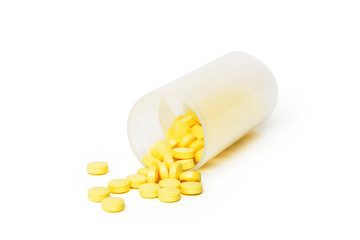 Yellow pills in a container on white