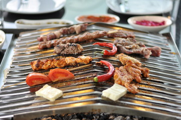Traditional Cypriot meze and mix meat and chicken kebab table with charcoal barbecue on the table for self cooking during the eating time