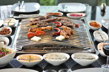 Traditional Cypriot meze and mix meat and chicken kebab table with charcoal barbecue on the table for self cooking during the eating time