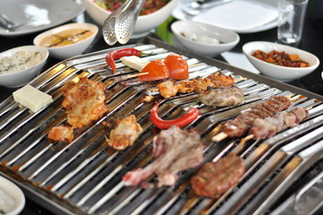 Traditional Cypriot meze and mix meat and chicken kebab table with charcoal barbecue on the table for self cooking during the eating time