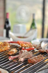 Traditional Cypriot meze and mix meat and chicken kebab table with charcoal barbecue on the table for self cooking during the eating time