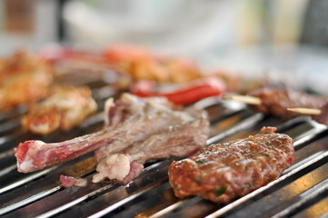 Traditional Cypriot meze and mix meat and chicken kebab table with charcoal barbecue on the table for self cooking during the eating time