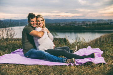 Husband and his pregnant wife enjoy spending time together outdoor.