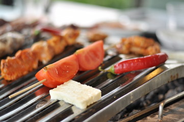 Traditional Cypriot meze and mix meat and chicken kebab table with charcoal barbecue on the table for self cooking during the eating time