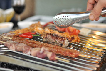 Traditional Cypriot meze and mix meat and chicken kebab table with charcoal barbecue on the table for self cooking during the eating time