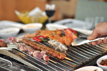 Traditional Cypriot meze and mix meat and chicken kebab table with charcoal barbecue on the table for self cooking during the eating time