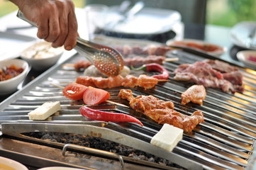 Traditional Cypriot meze and mix meat and chicken kebab table with charcoal barbecue on the table for self cooking during the eating time