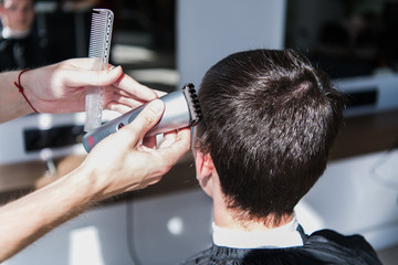 Close-up, master hairdresser does hairstyle and style with scissors and comb. Concept Barbershop
