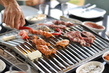 Traditional Cypriot meze and mix meat and chicken kebab table with charcoal barbecue on the table for self cooking during the eating time