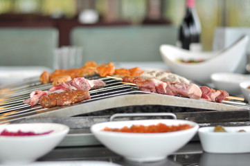 Traditional Cypriot meze and mix meat and chicken kebab table with charcoal barbecue on the table for self cooking during the eating time