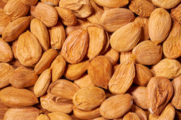 Scattered almond nuts on a brown background. Selective focus