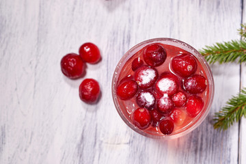 Glasses with cranberry juice on white wooden background with pine branch in the background. Christmas tre. Copy space