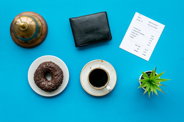 Pay the bill, pay at restaurant. Check near wallet, service bell, coffee on blue background top view