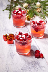 Glasses with cranberry juice on white wooden background with pine branch in the background. Christmas tree