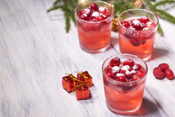 Glasses with cranberry juice on white wooden background with pine branch in the background. Christmas tre. Copy space