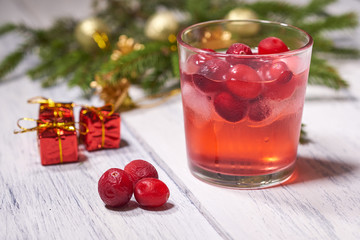 Glasses with cranberry juice on white wooden background with pine branch in the background. Christmas tree