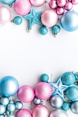 Christmas and New Year symbols. Toys for festive tree. Blue and pink balls and stars on white background top view copy space border