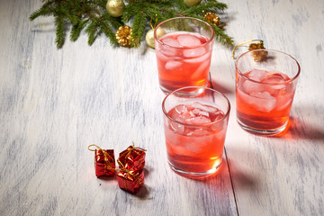 Glasses with cranberry juice on white wooden background with pine branch in the background. Christmas tre. Copy space