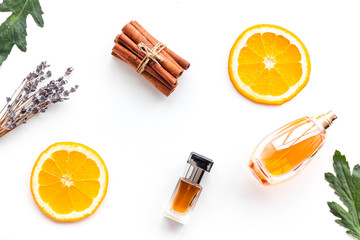 Sweet perfume with fruit fragrance. Bottle of perfume near orange, lavender, cinnamon on white...