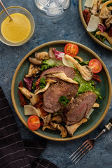 Salad with warm beef with oyster mushrooms, tomatoes and greens. Top view