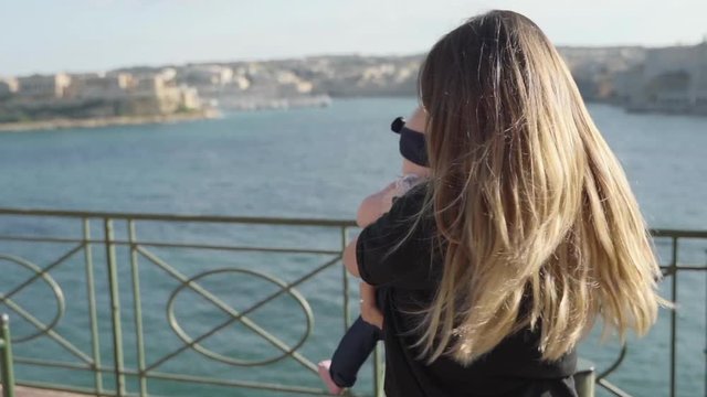 Close up view of beautiful young mother playing with her adorable daughter, mother holds baby on her arms and spins around.