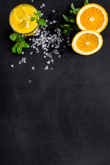 Orange juice and citrus cocktails. Juice in glass near cut orange and lemon, crushed ice, green mint on black background top view space for text