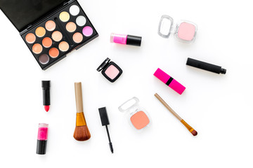 visagiste desk with decorative cosmetics: eyeshadows, lipstick, brush white background top view