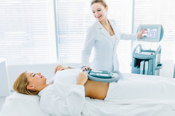 Fototapeta premium Professional caucasian female cosmetologist, Doctor, holding a modern medical hardware equipment for body shape correction, close up, weight loss, body care concept