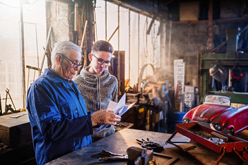 A grandfather and his grandson restoring an old pedal car